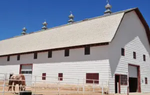 A white barn with four large domed roofs.