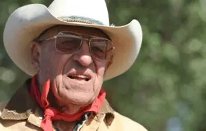 A man in cowboy hat and glasses with red bandanna.